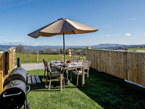 a table with an umbrella and chairs and a grill at 2 Bed in Blackburn oc-finch in Blackburn