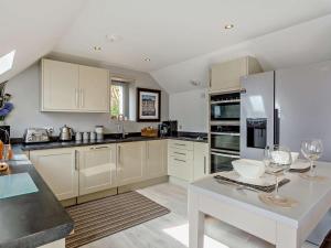 a kitchen with white cabinets and a table with wine glasses at 1 Bed in Crieff oc-58797 in Saint Fillans