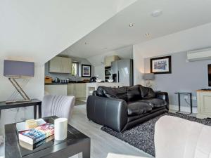 a living room with a black leather couch and a kitchen at 1 Bed in Crieff oc-58797 in Saint Fillans