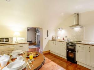 a kitchen with white cabinets and a wooden table at 1 Bed in Crieff oc-87498 in Crieff