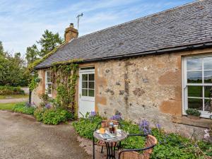 a stone cottage with a table and chairs in front of it at 2 Bed in Dingwall oc-ca387 in Cononbridge
