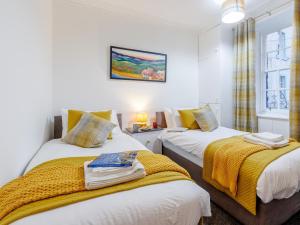 a bedroom with two beds with yellow blankets and a window at 2 Bed in Anstruther oc-80648 in Pittenweem