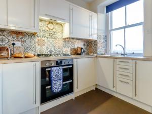 a kitchen with white cabinets and a stove and a window at 2 Bed in Anstruther oc-80648 in Pittenweem +10 photos