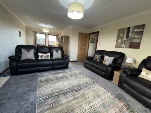 a living room with black leather couches and a rug at 3 Bed in Newton Stewart oc-87541 in Mochrum