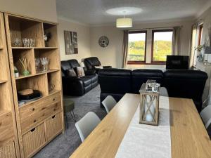 a living room with a table and a black leather couch at 3 Bed in Newton Stewart oc-87541 in Mochrum