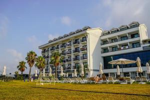 a hotel with chairs and umbrellas in front of it at Armella Hill Hotel in Side
