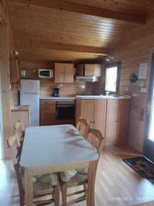 a kitchen with a table and chairs in a cabin at La Taillade de Montségur location de Chalets en bois in Fougax-et-Barrineuf