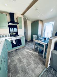 a kitchen with green cabinets and a table with a stove at SEA VIEW CARAVAN Disability friendly in Caister-on-Sea