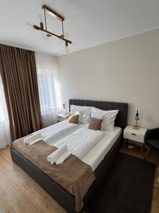 a bedroom with a large bed with white sheets at Európa Apartman Mini in Békéscsaba