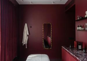 a bedroom with a mirror on a red wall at Wellesley Hotel in Pune