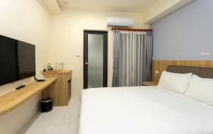 a hotel room with a bed and a television at Hualien Leo and Alley Elevator B&B in Hualien City