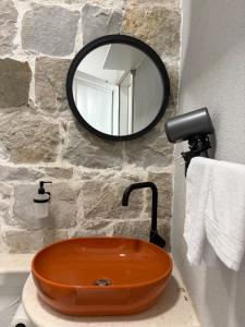 a bathroom with an orange sink and a mirror at Bright Romantic Studio near sea in Kaštela