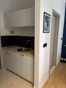 a kitchen with white cabinets and a sink at Bright Romantic Studio near sea in Kaštela +10 photos
