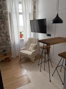 a living room with a desk and a chair and a television at Bright Romantic Studio near sea in Kaštela
