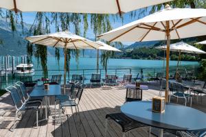 eine Terrasse mit Tischen, Stühlen und Sonnenschirmen in der Unterkunft lofthotel Walensee in Murg