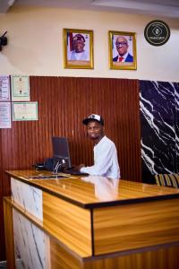 Ein Mann sitzt an einem Schreibtisch mit einem Laptop. in der Unterkunft Ozigrand Hotel in Benin-Stadt