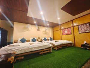 two beds in a room with green carpet at Tusker Tea County in Mal bazar
