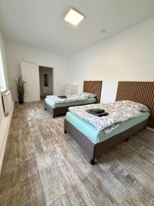 two beds in a large room with wooden floors at Modernes Apartment im Grünen in Kroppach