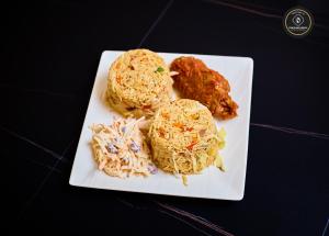 ein weißer Teller mit Essen auf einem Tisch in der Unterkunft Ozigrand Hotel in Benin-Stadt + 32 Fotos