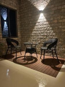 two chairs and a table in a room with a brick wall at The Mishkan Apartments in Kaduna