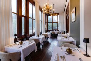 a restaurant with white tables and chairs and windows at The Cape Town Club in Cape Town