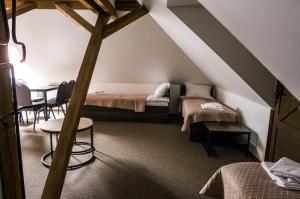 a attic room with two beds and a table at Viešbutis DYVAI in Kupiškis