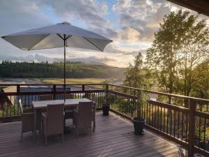 a wooden deck with a table and an umbrella at 4 Bed in Kippford oc-95234 in Kippford