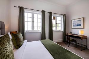 a bedroom with a bed and a desk and windows at The Cape Town Club in Cape Town