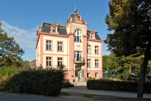 a pink building with a tower on top of it at Waren Müritz Hotel Harmonie in Waren