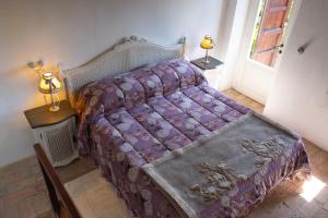 a bedroom with a bed with a purple comforter at Casa Torre Adults Only storia e relax a Fiorenzuola in Fiorenzuola di Focara