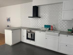 a kitchen with white cabinets and a stove and sink at Charmigt boende på i centrala Helsingborg in Helsingborg