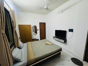 a small bedroom with a bed and a tv at manoj lodge in Sangamner