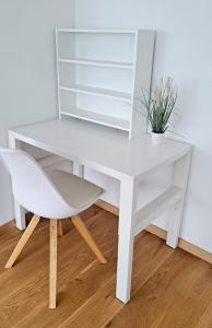 a white desk and a chair with a plant at City Apartment Starnberg in Starnberg