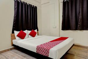 a bedroom with a large bed with red pillows at Hotel O Sai Avenue in Pune