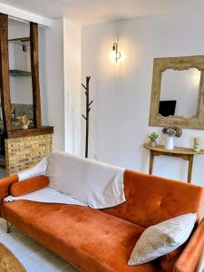 an orange couch in a living room with a mirror at Cocon détente & Jacuzzi(Balnéo) in Dieppe