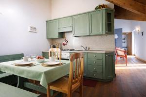 a kitchen with green cabinets and a table with chairs at LA PULCE INNEVATA - Mansarda a due passi dal cielo - Dolomiti Affitti in Passo Rolle