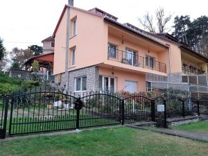 a pink house with a black fence in front of it at Keltafok Apartman, Balatonföldvár in Balatonföldvár