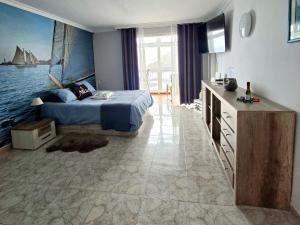 a bedroom with a bed with a painting on the wall at Ocean Whisper suite in Tacoronte