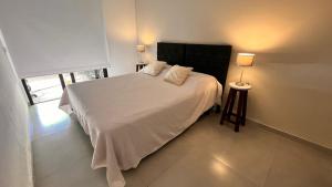 a bedroom with a large white bed and a window at Piccolo Posto in Neuquén