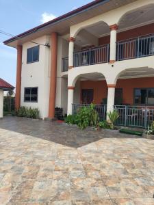 a large white house with a brick patio at Steco rental in Amasaman
