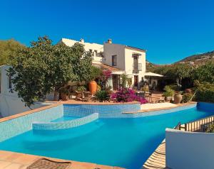 a swimming pool in front of a house at Finca Los Arcos Bed and Breakfast Comares Malaga in Comares