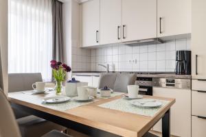 a kitchen with a table with plates and flowers on it at K & R Appartements Binz in Binz