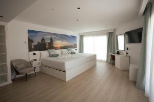 a white bedroom with a large bed and a chair at Hotel Villa España in Benidorm