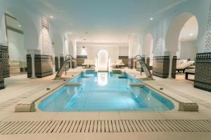a swimming pool in a building with blue water at Hotel Villa España in Benidorm