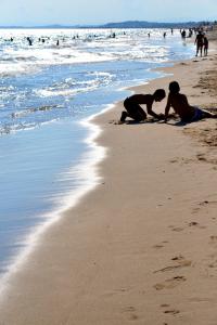 dos personas sentadas en la arena en la playa en Villa service - Casa Jordi, en Segur de Calafell
