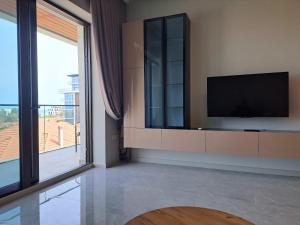 a living room with a tv and a large window at Sea Breeze Nardaran open kitchen apartment in Nardaran