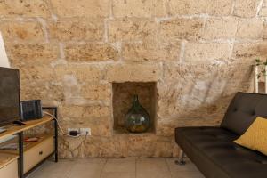 a living room with a stone wall with a couch at Maison de Sisine in Capurso