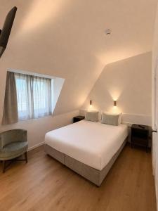 a bedroom with a large white bed and a chair at Strandhotel De Haan in De Haan +21 photos