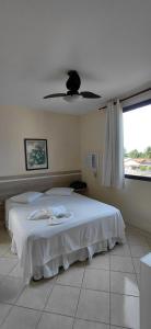 a bedroom with a white bed with a ceiling fan at Pousada Costa do Sol in Aracruz