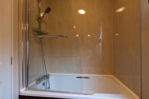 a bath tub with a shower with a glass door at Rivendale Lodge in Port Seton +10 photos